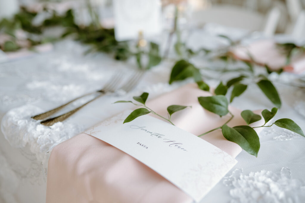 Place setting with place card wrapped around napkin and greenery