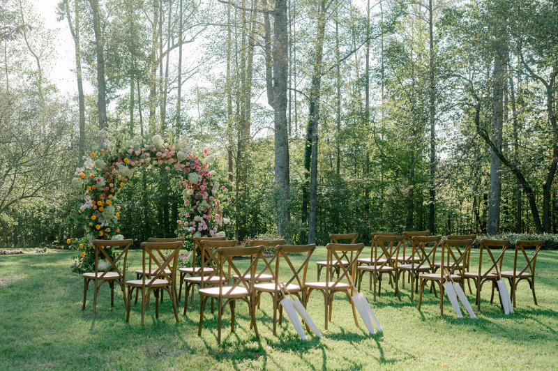 OUTDOOR WEDDING CEREMONY SET UP WITH CHAIRS AND A FLORAL CEREMONY ARCH